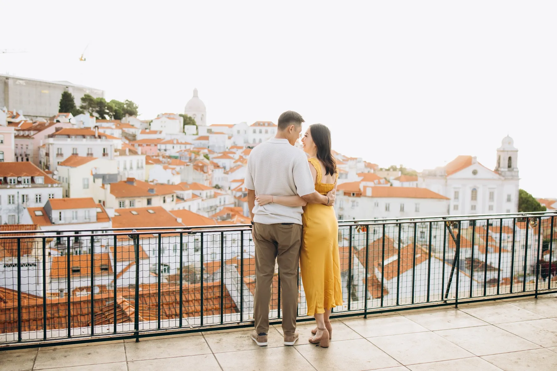 Couple at an Alfama viewpoint with the rooftops of Lisbon behind them