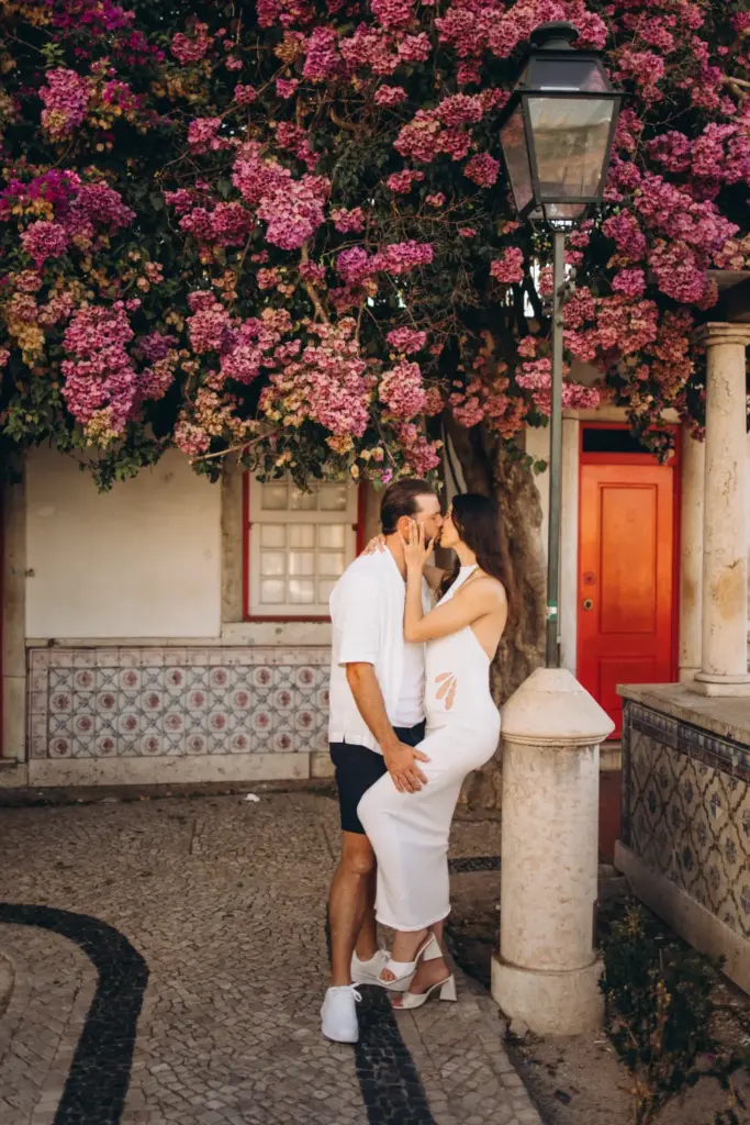 Couple by a red door under bougainvillea in Alfama