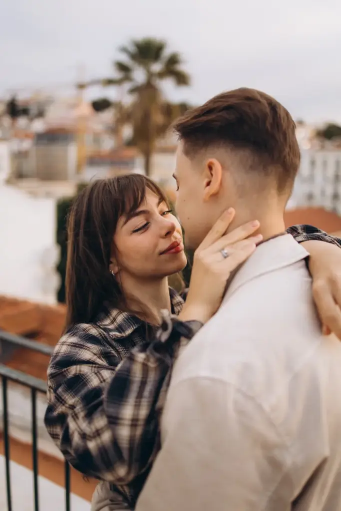 Couple kissing at a viewpoint, a palm tree behind them