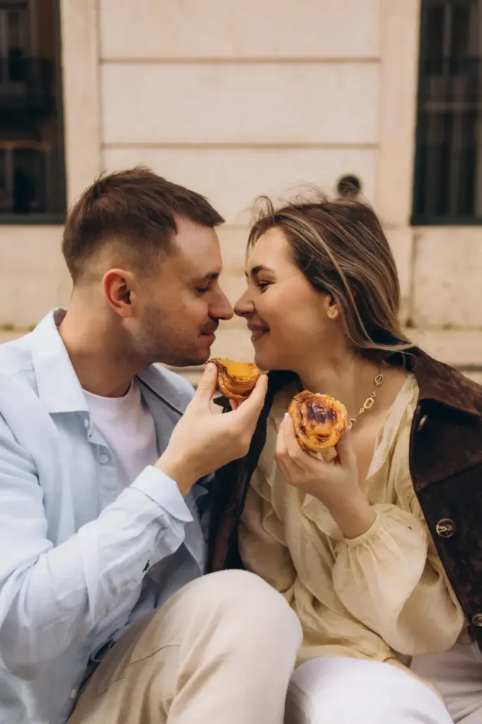 Couple laughing while sharing a pastry on a Lisbon street