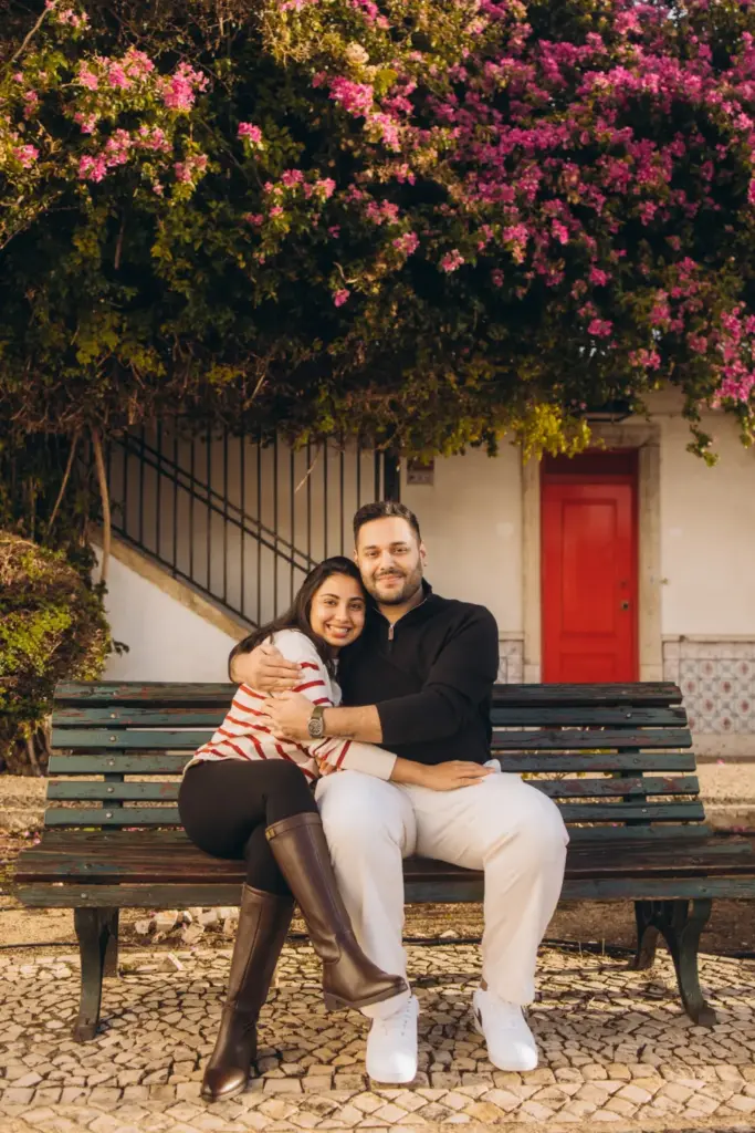 Couple on a bench under bougainvillea by a red door