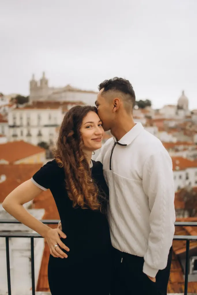 Couple at an Alfama viewpoint, São Vicente church behind them