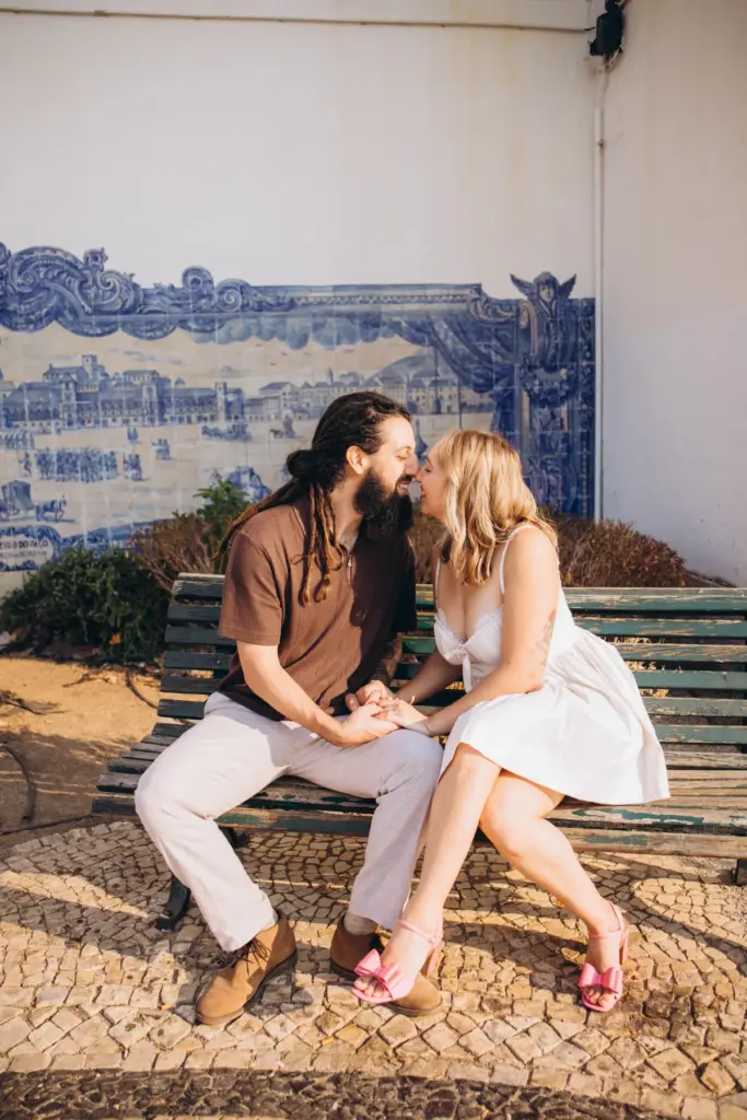 Couple on a bench in front of a blue azulejo tile panel in Alfama