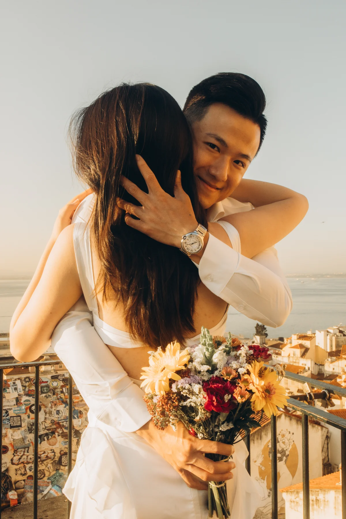 Couple with a bouquet embracing at a Lisbon viewpoint at sunrise