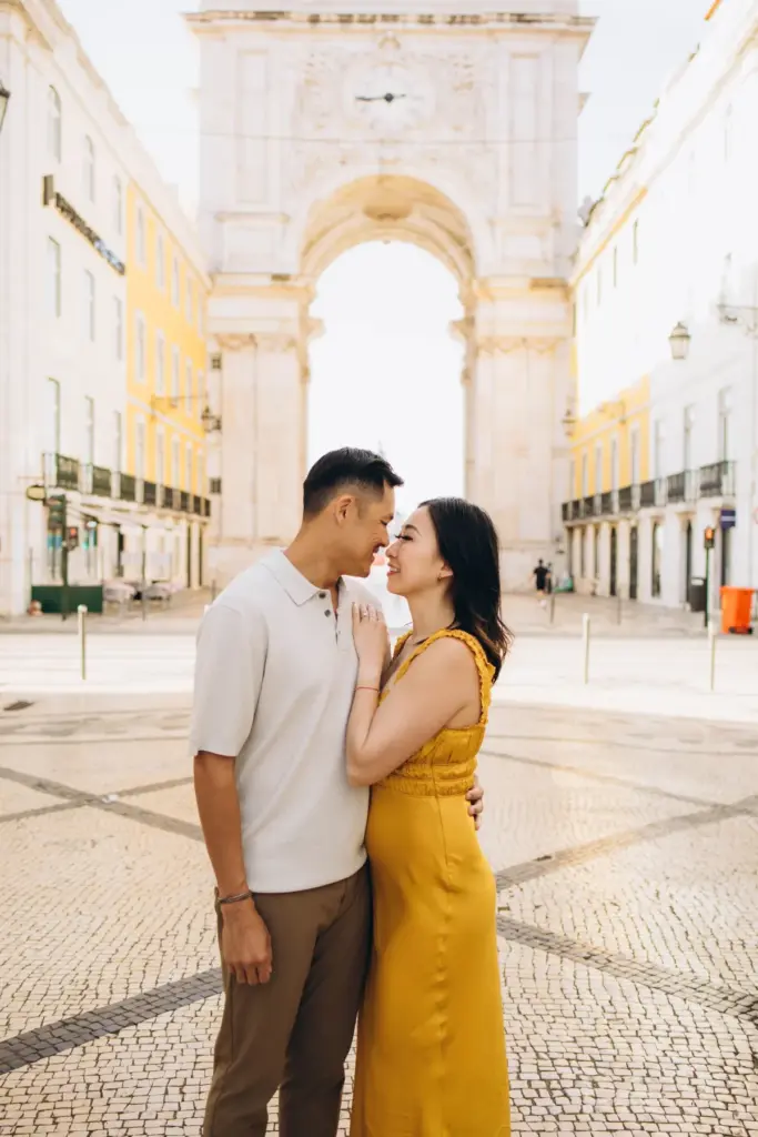 Couple close together in front of the Rua Augusta Arch