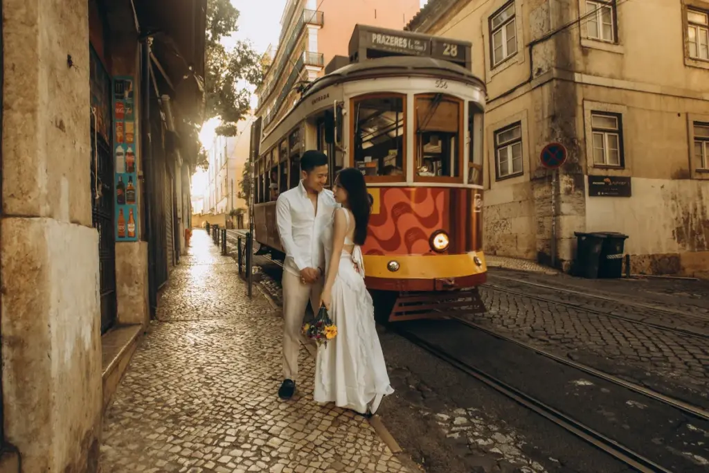 Couple on a cobbled street as a red tram passes in Alfama