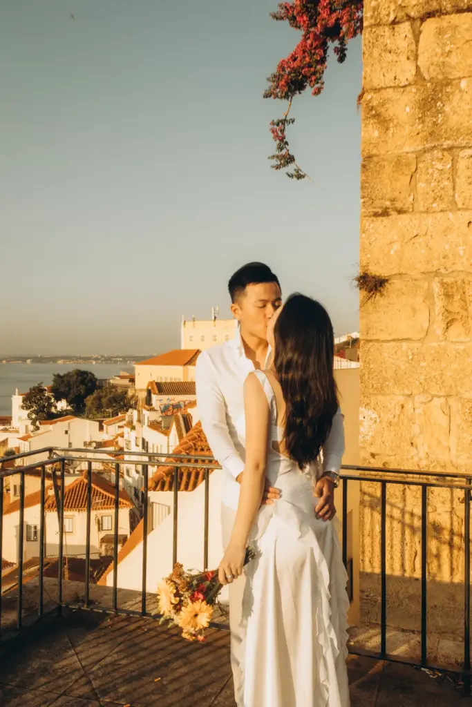 Couple embracing by an old stone wall at an Alfama viewpoint