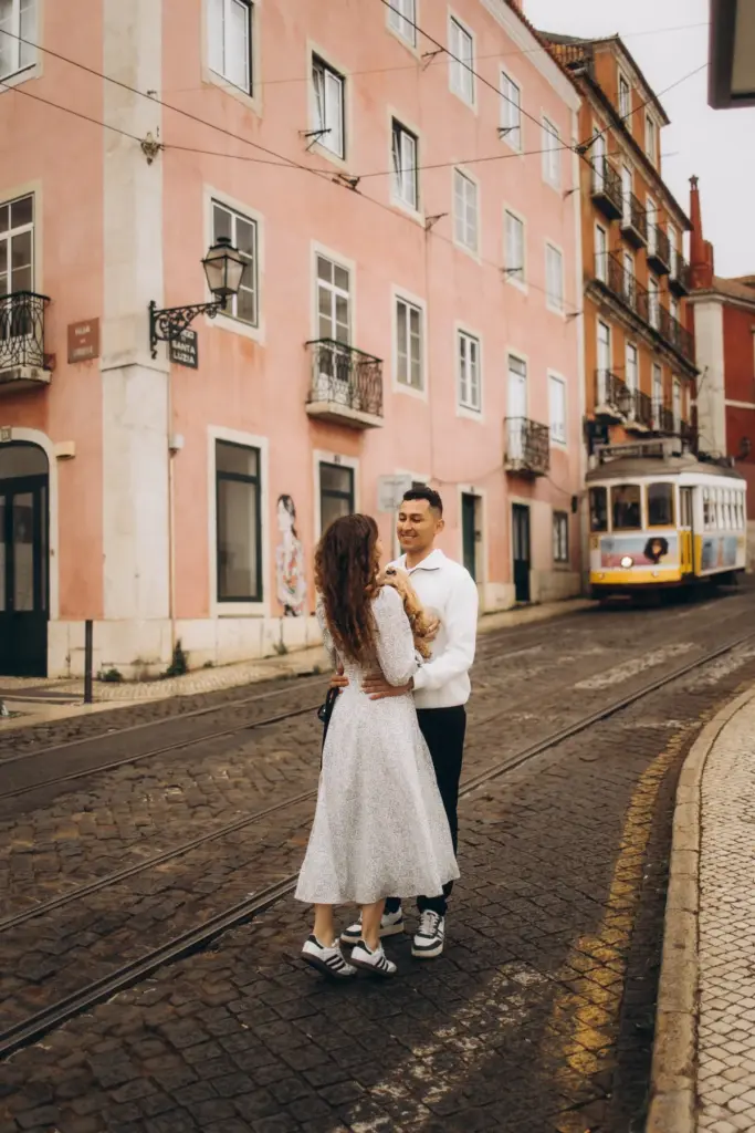 Couple embracing on a tram street in Lisbon, a yellow tram behind them