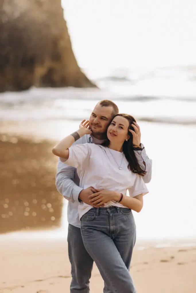Couple embracing at the water's edge at Praia da Adraga