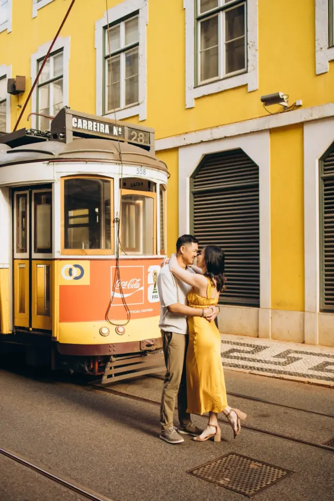 Couple embracing beside a yellow tram in Baixa