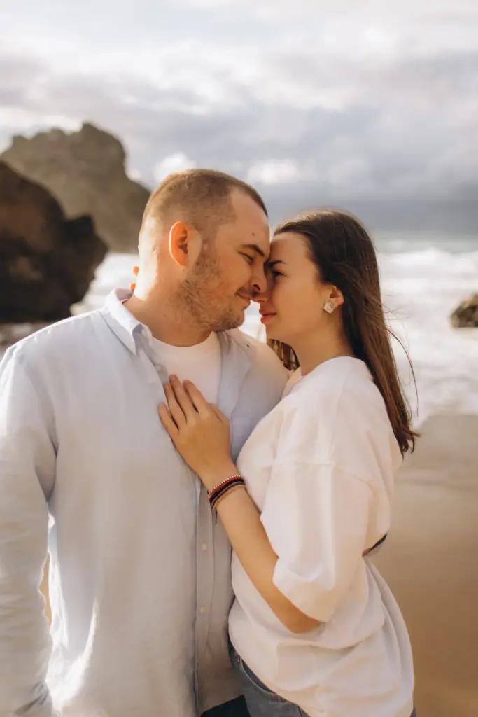 Couple forehead to forehead on the beach at Praia da Adraga