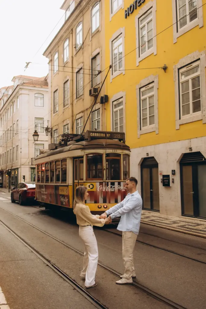 Couple holding hands on the tram rails as a yellow tram passes