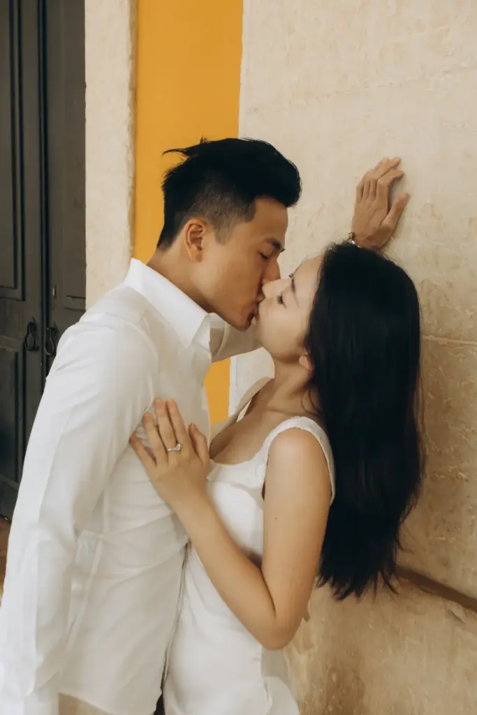 Couple kissing against a yellow wall in Lisbon