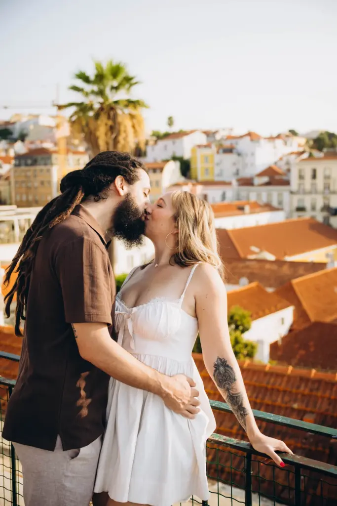 Couple kissing by a palm tree above the rooftops of Alfama