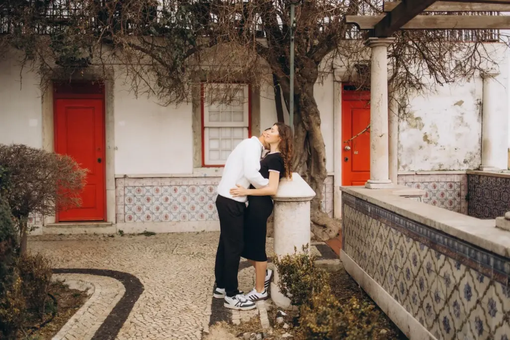 Couple kissing by a red door at Santa Luzia, their dog beside them
