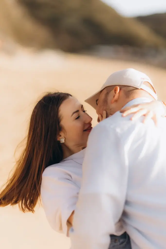 Couple laughing together on the sand at Praia da Adraga