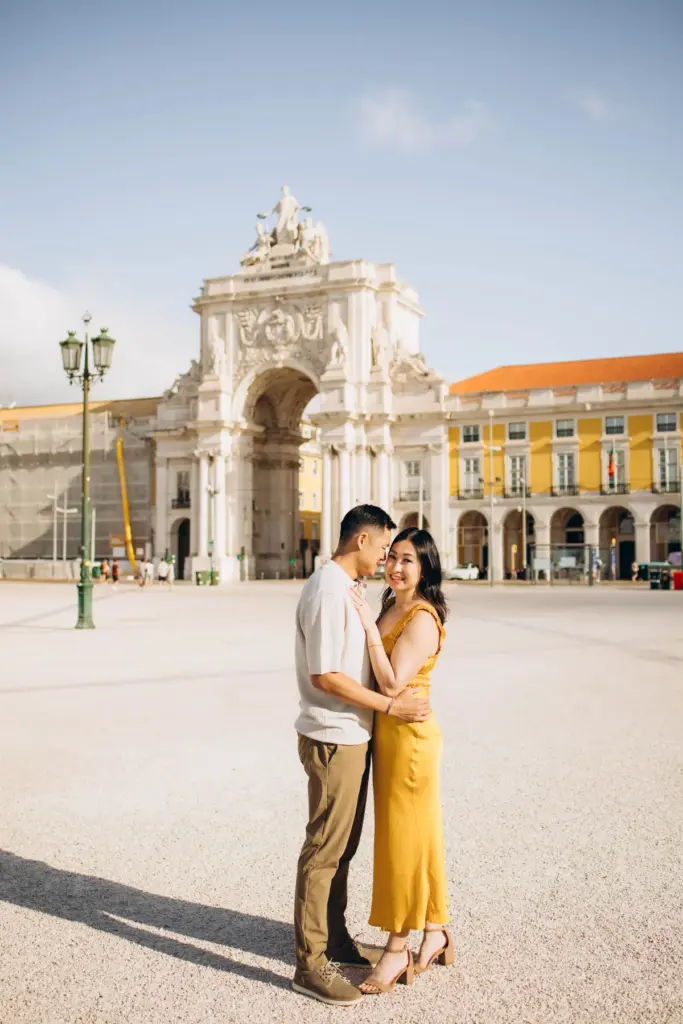 Couple at Praça do Comércio with the arch and the yellow arcades behind them