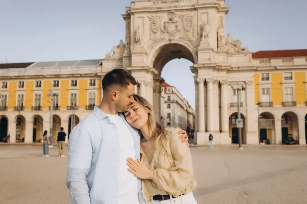 Couple at Praça do Comércio with the Rua Augusta Arch behind them