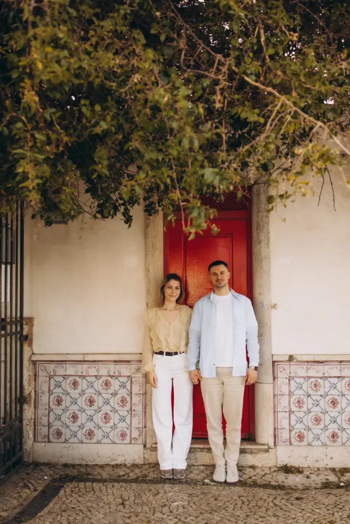 Couple by a red door framed by blue tiles in Alfama