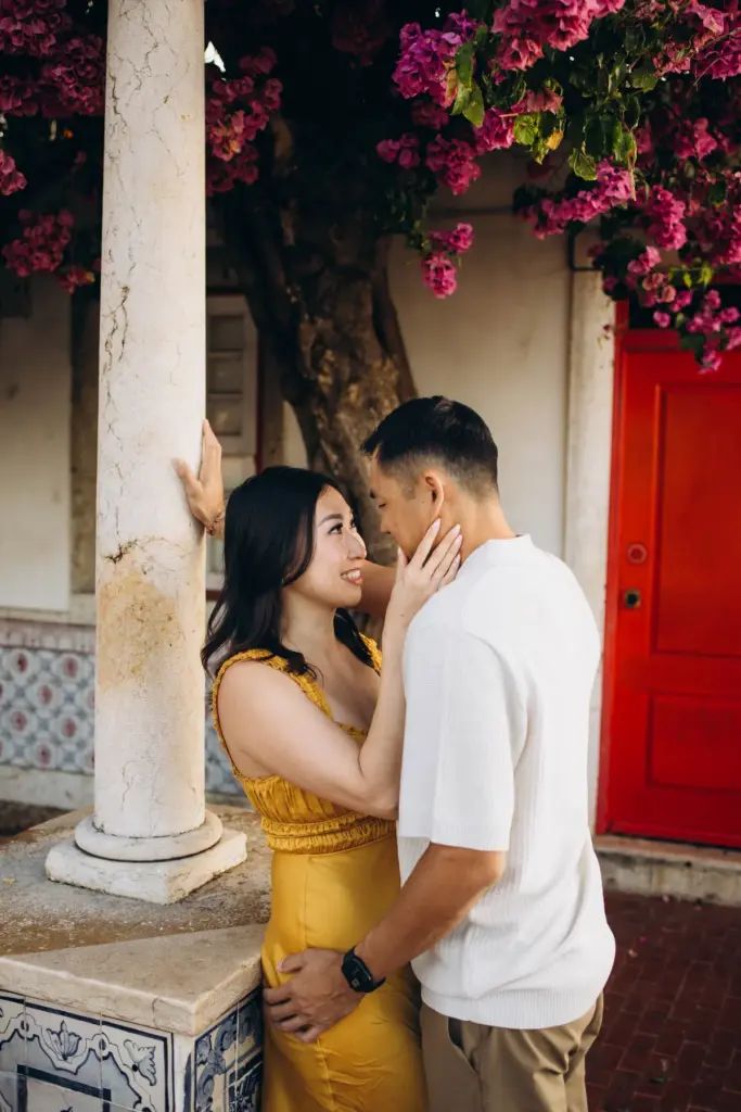 Couple by a red door under bougainvillea in Alfama