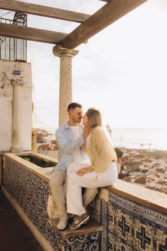 Couple sitting close on the tiled wall at Santa Luzia viewpoint
