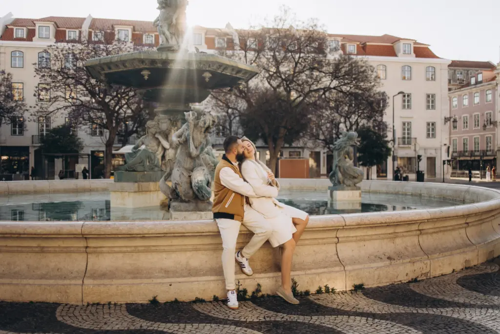 Couple sitting on the rim of a baroque fountain in Rossio square, Lisbon