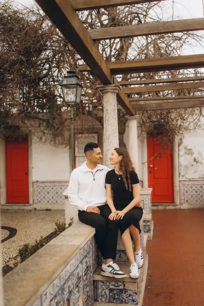Couple sitting on the Santa Luzia tiled wall by the red doors