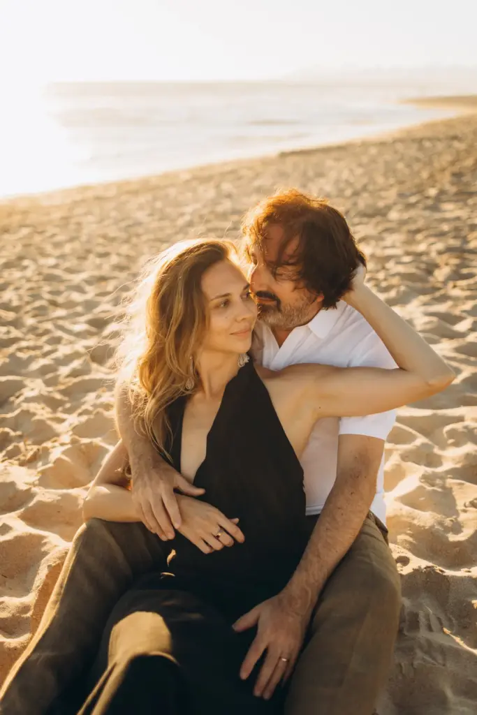 Couple sitting together on the sand at Costa da Caparica