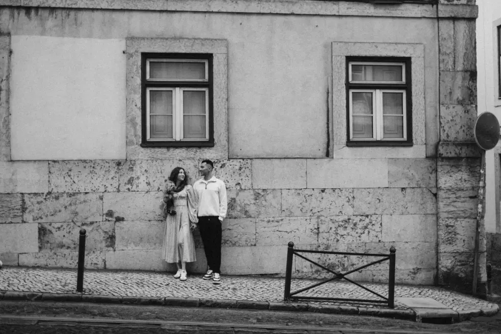 Couple by a stone wall in Alfama, black and white