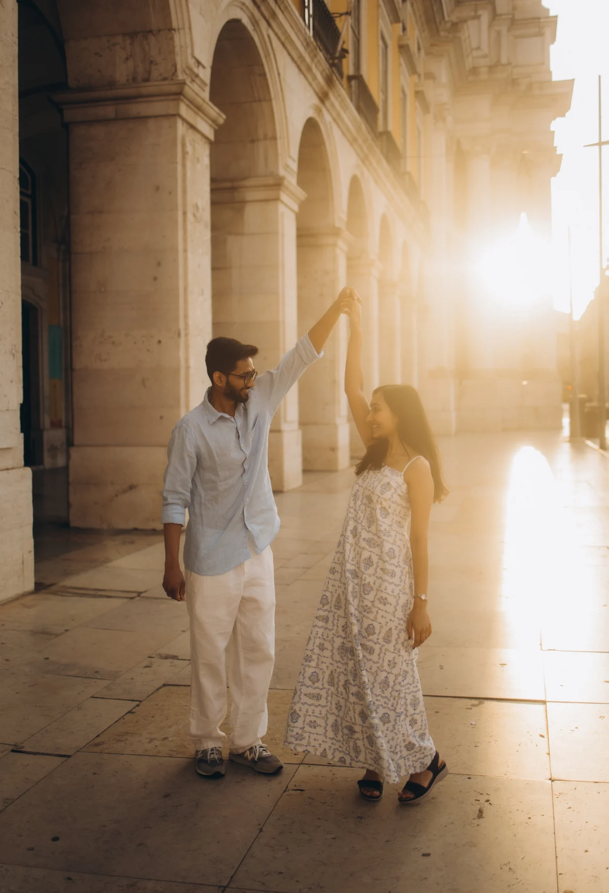 Couple under the arcades of Praça do Comércio at sunrise