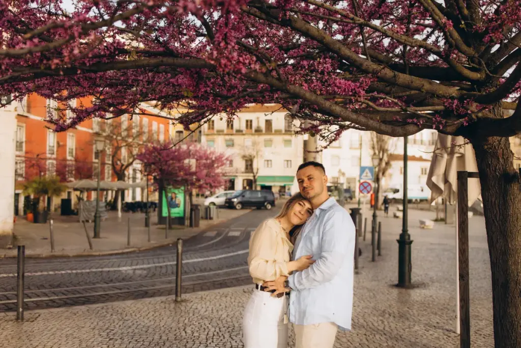 Couple under pink blossom trees in Lisbon