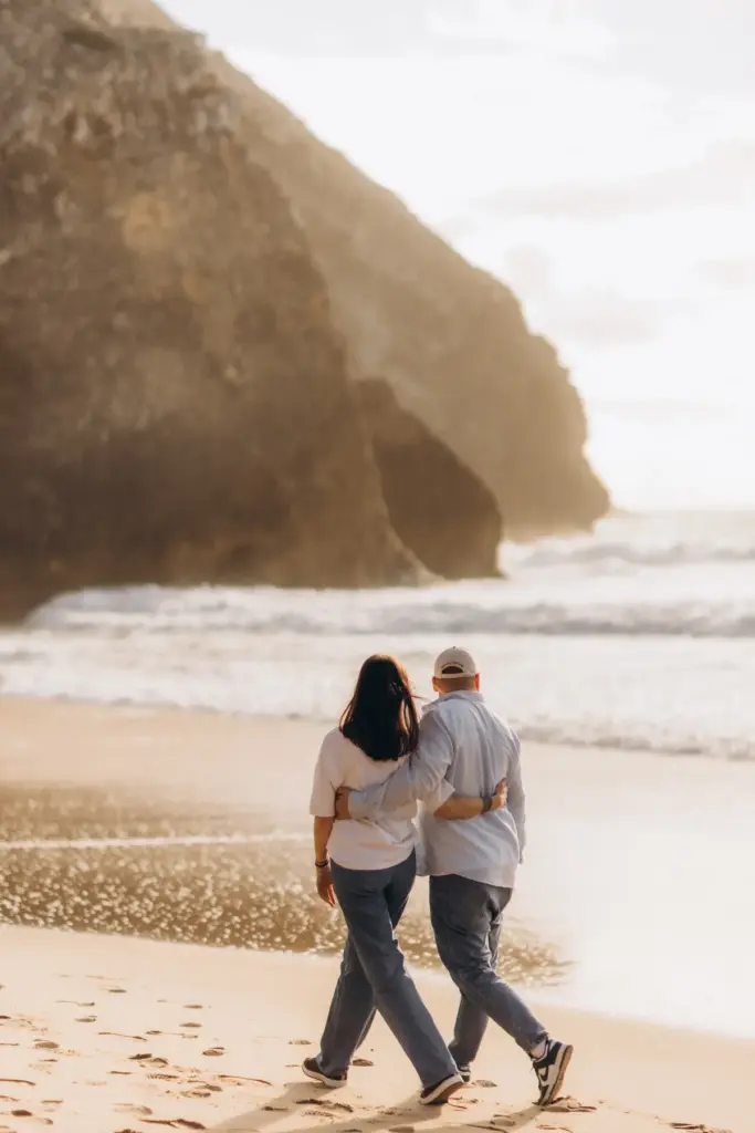 Couple walking arm in arm below the cliffs of Praia da Adraga