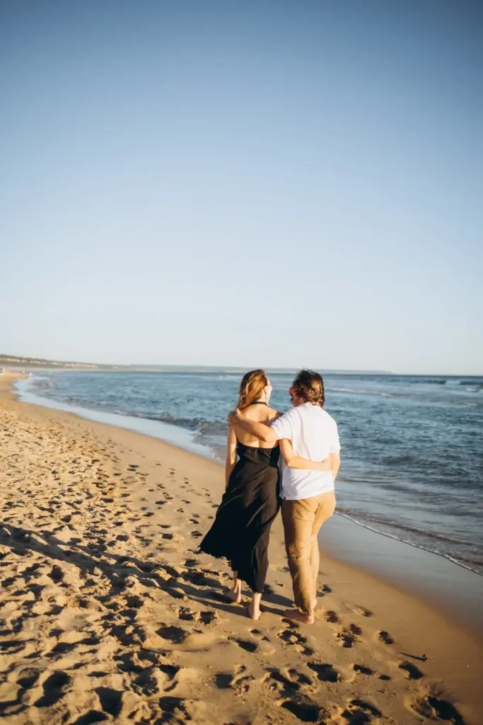 Couple walking arm in arm by the sea at Costa da Caparica