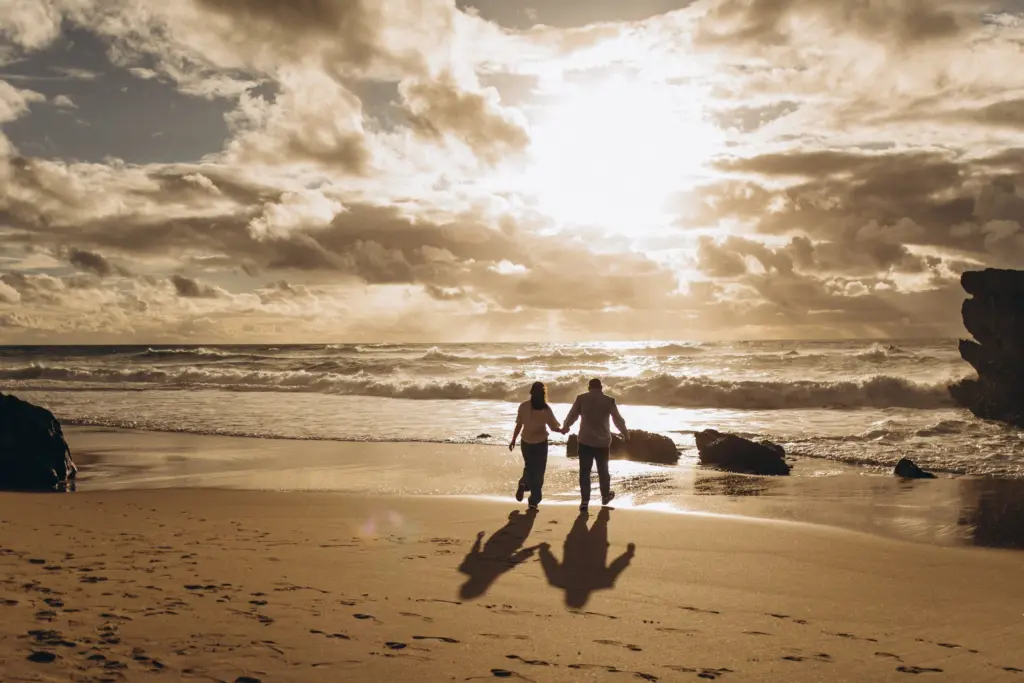 Couple walking on an Atlantic beach at sunset