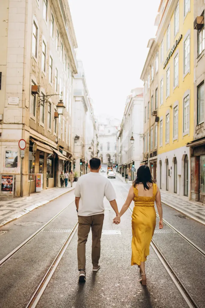Couple walking hand in hand down Rua Augusta