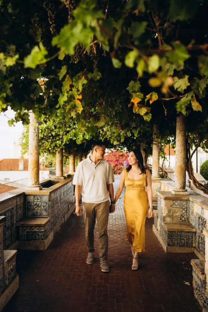 Couple walking hand in hand under the vine pergola at Santa Luzia