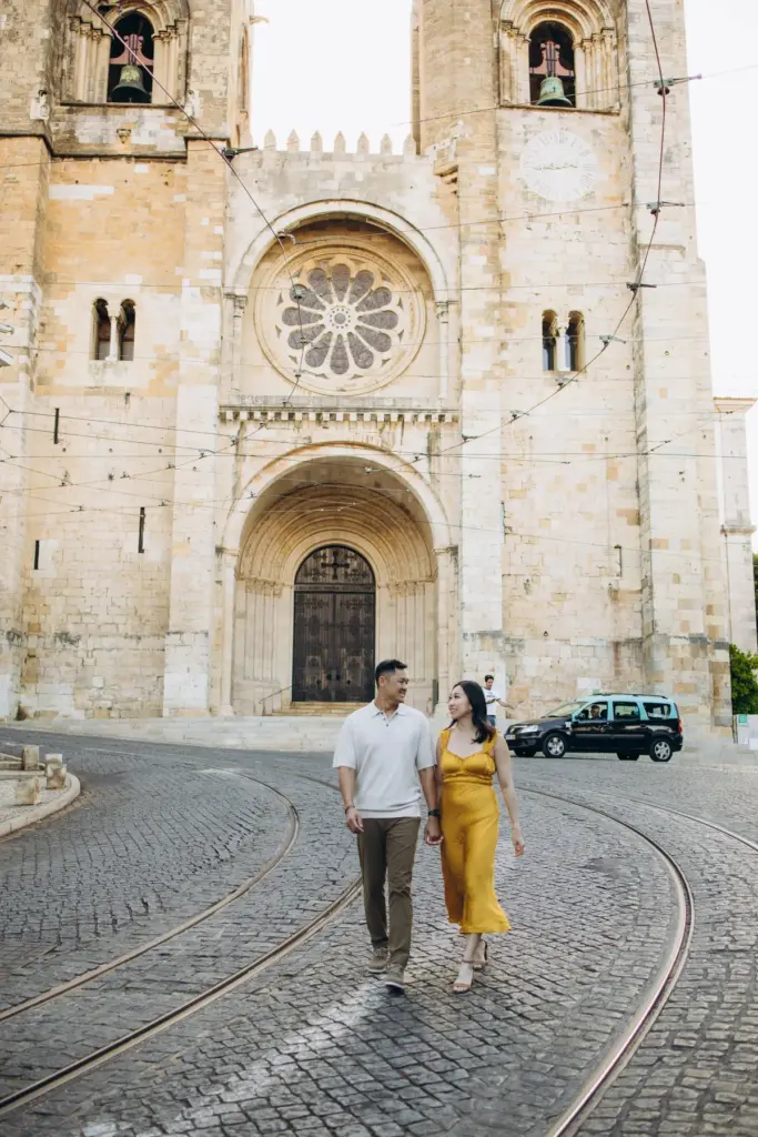 Couple walking past Lisbon Cathedral on the tram rails