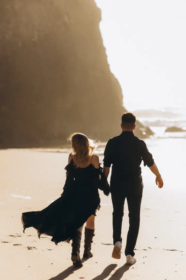 Couple walking on Praia da Adraga below the cliffs
