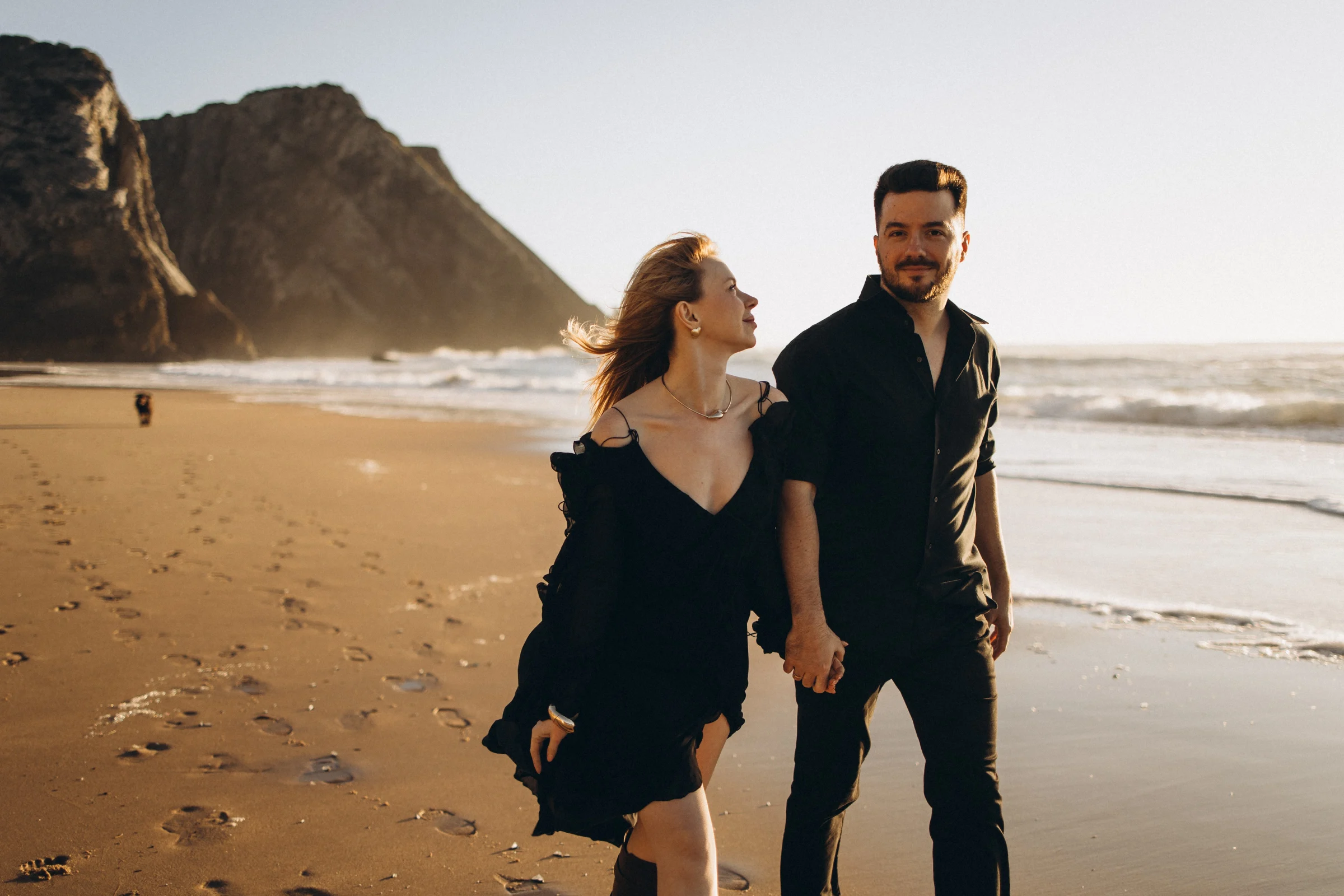 Couple walking on Praia da Adraga below the cliffs