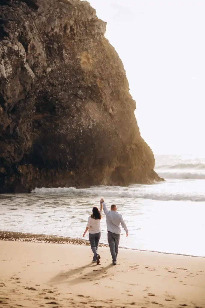 Couple walking towards the sea under the cliffs of Praia da Adraga