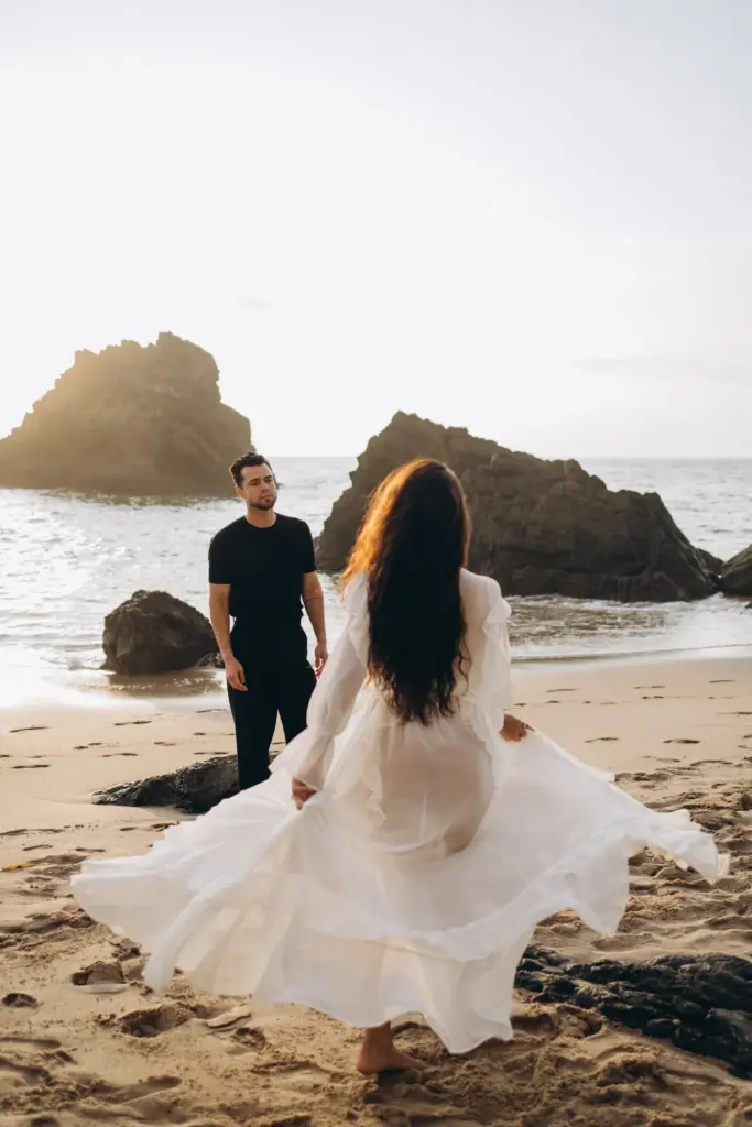 Woman spinning in a white dress as her partner watches, Praia da Adraga