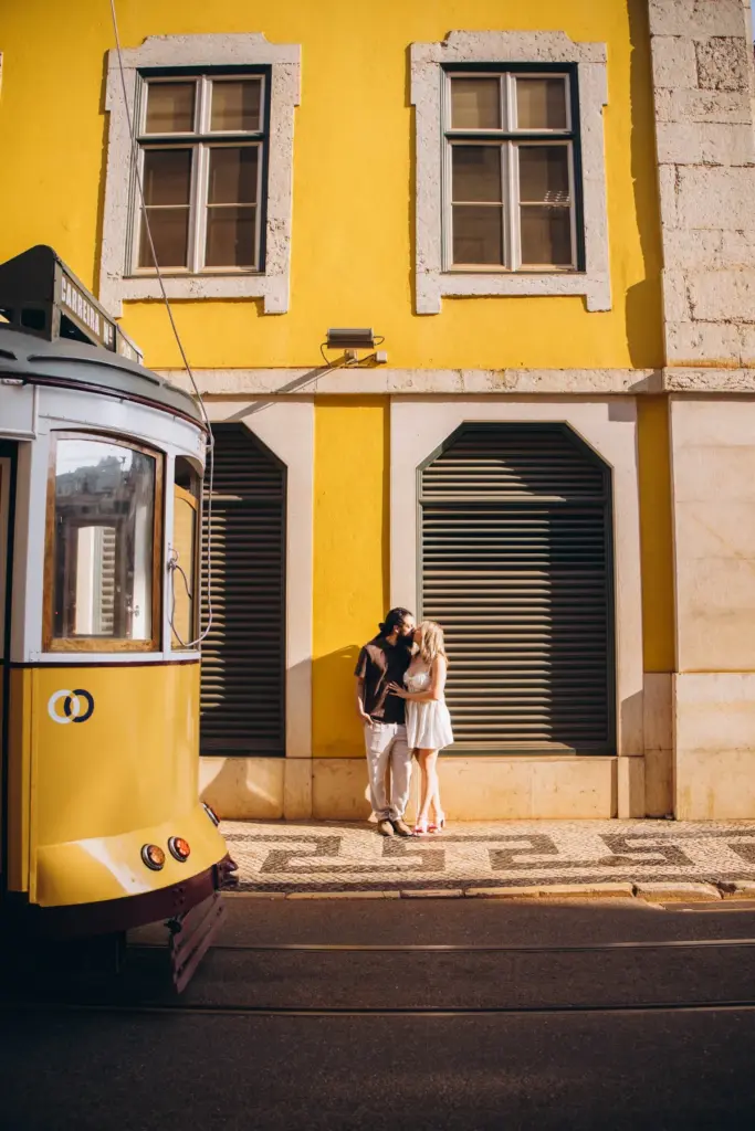 Couple between a yellow tram and a yellow building in Lisbon