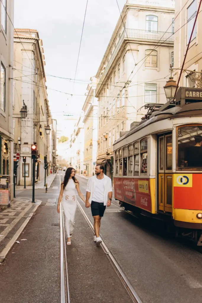 Couple walking beside a tram on a Lisbon street
