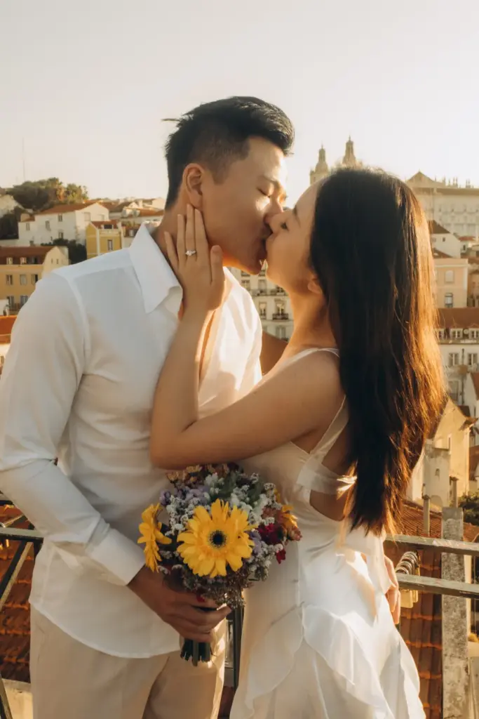 Couple with a bouquet kissing at a viewpoint at sunrise