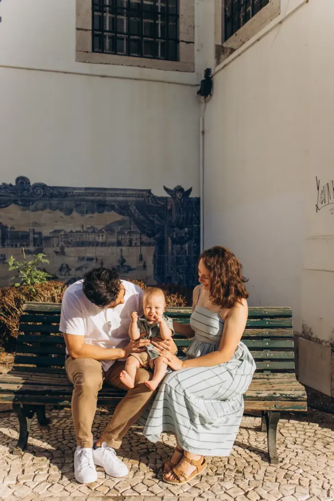 Family with a baby on a bench by a blue azulejo tile panel in Alfama