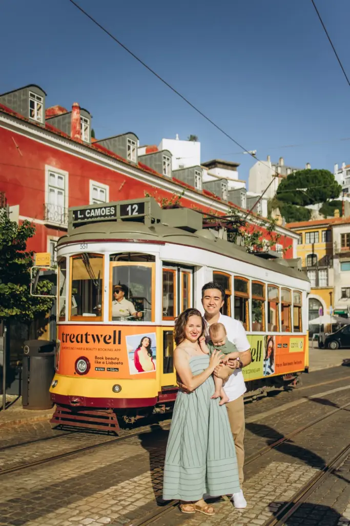 Family with their baby beside a yellow tram in Alfama