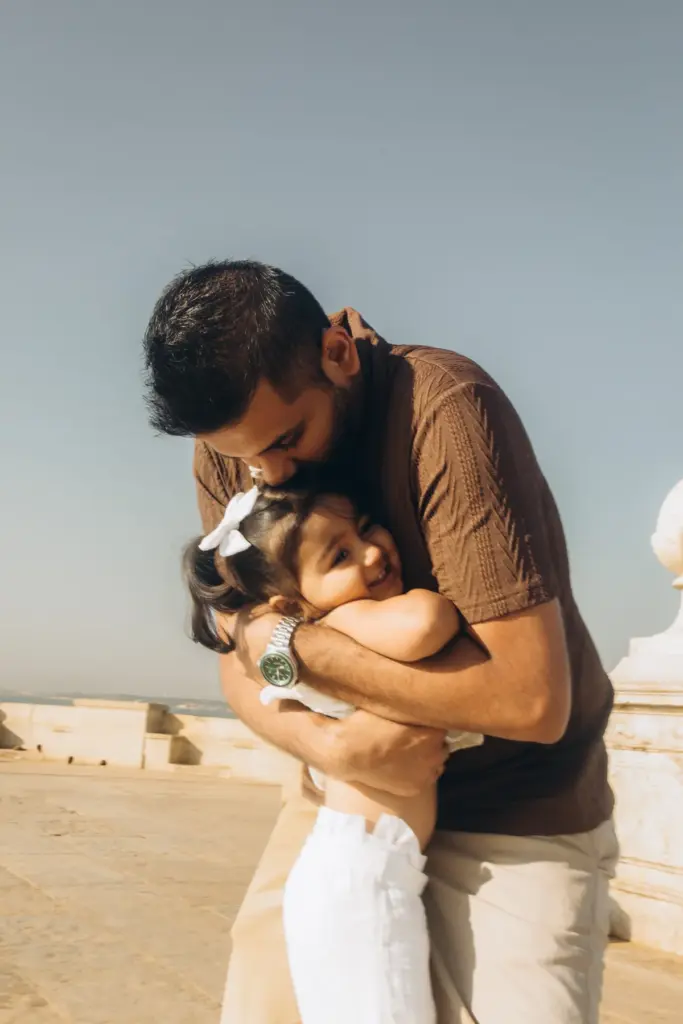 Father hugging his little daughter by the river in Lisbon