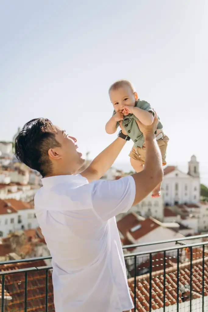 Father lifting his baby into the air above Alfama