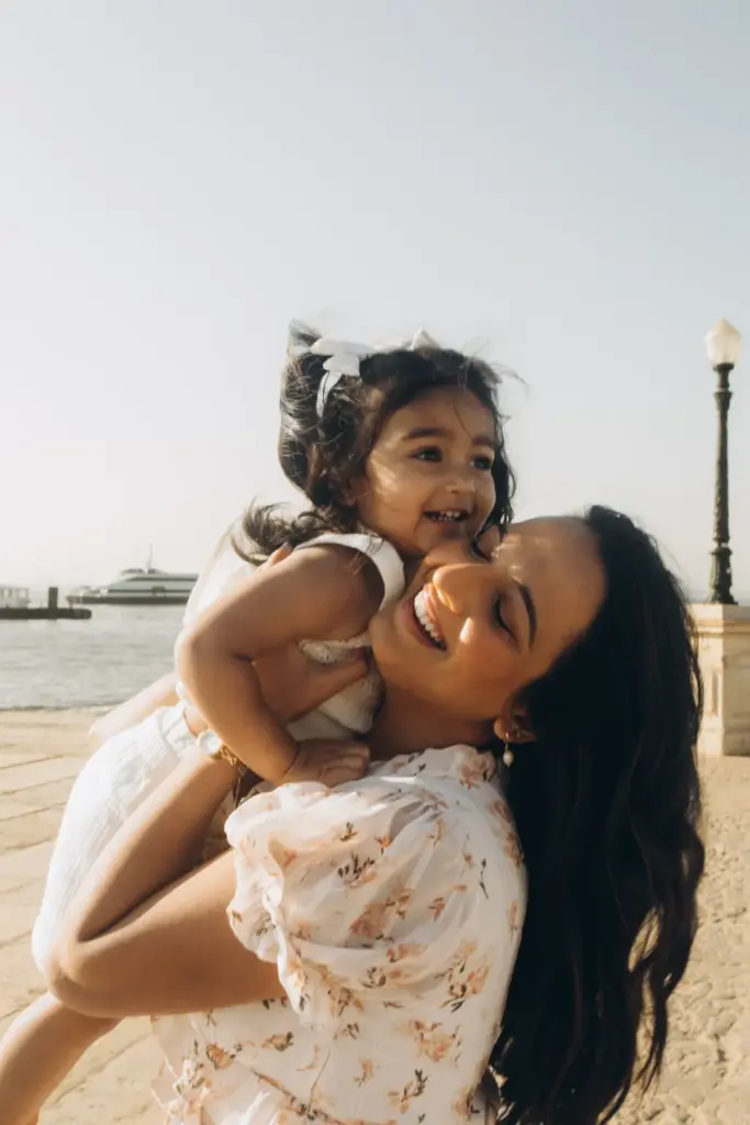 Mother lifting her laughing daughter on the Lisbon riverfront