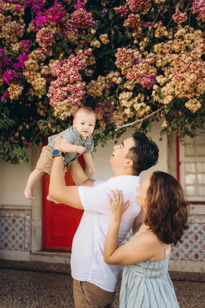 Parents lifting their baby under bougainvillea